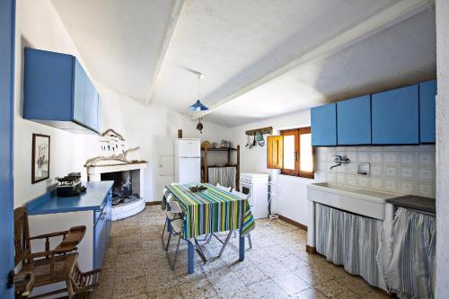 a kitchen with blue cabinets and a table with a table cloth at Ferienhaus Stazzo Mit Garten In Luogosanto in Luogosanto