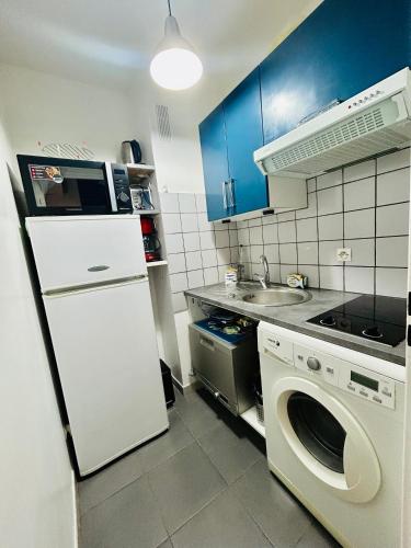 Il comprend une cuisine équipée d'un réfrigérateur blanc et d'un lave-linge. dans l'établissement Studio une brise marine, à Trouville-sur-Mer