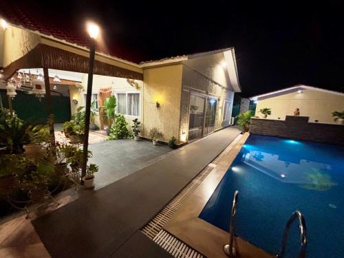 a house with a swimming pool at night at GoBravo 37 - 2Bhk Farm with Pool & Garden Sec150 Noida in Greater Noida