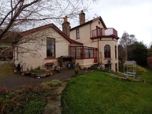 ein großes weißes Haus mit einer Veranda und einem Hof in der Unterkunft Strathpeffer Holiday Cottages in Strathpeffer