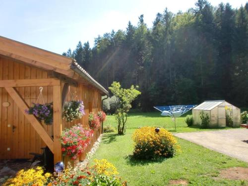 a garden with flowers and a building with a fence at Ferienhaus In Röhrnbach Mit Grill Und Terrasse in Röhrnbach