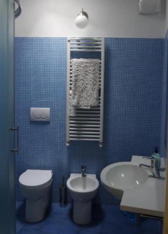 a blue tiled bathroom with a toilet and a sink at Al villino Duse in Genova