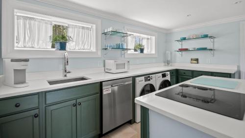 una cocina con armarios verdes y encimeras blancas en Hosta Cottage - Beautiful, Waterfront, Luxury, en New Church