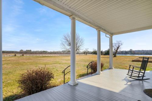a porch with two chairs and a view of a field at Huntington Farm - Pristine Historical Home Overlooking Cherrystone Creek! in Cape Charles