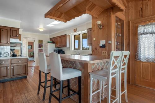 a kitchen with wooden cabinets and a island with bar stools at Huntington Farm - Pristine Historical Home Overlooking Cherrystone Creek! in Cape Charles