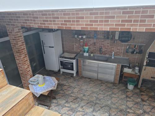 a brick kitchen with a sink and a refrigerator at Pousada da Nina in Itanhaém