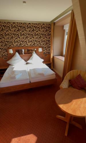 a bedroom with a bed and a table and a chair at Friedchens Gasthof an der Möhne in Warstein