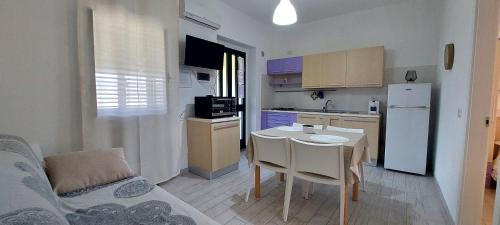 a small kitchen with a table and a white refrigerator at Zwei Zimmer Penthouse Wohnung Mit Terrasse Mit Meerblick in Peschici