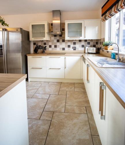 a kitchen with white cabinets and a tile floor at Harvest House with Games Room in Stirling
