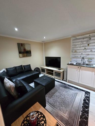 ein Wohnzimmer mit einer schwarzen Couch und einer Küche in der Unterkunft Cozy Cabin in Midrand