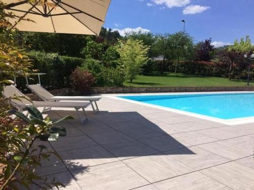 a pool with a chair and an umbrella next to it at Ferienhaus In Gallicano Mit Garten Und Pool in Gallicano