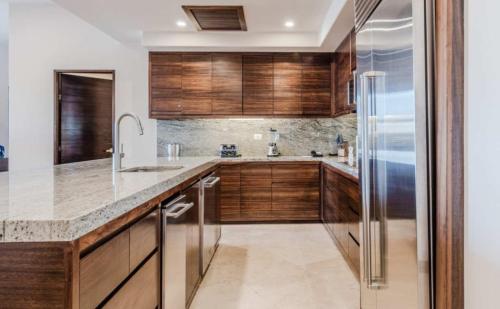 カボ・サン・ルーカスにあるOceanfront 3BR Condo at Diamante by The Agency Bajaのキッチン(木製キャビネット、冷蔵庫付)