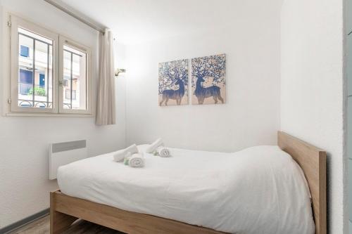 une chambre blanche avec un grand lit blanc et une fenêtre dans l'établissement Family Sea view with pools near shops and beaches, à Cannes