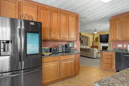 a kitchen with wooden cabinets and a stainless steel refrigerator at Isla Villa - Comfortable Bay Creek townhome with pools & golf! in Cape Charles