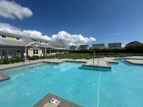 a large pool with blue water in front of a building at Isla Villa - Comfortable Bay Creek townhome with pools & golf! in Cape Charles