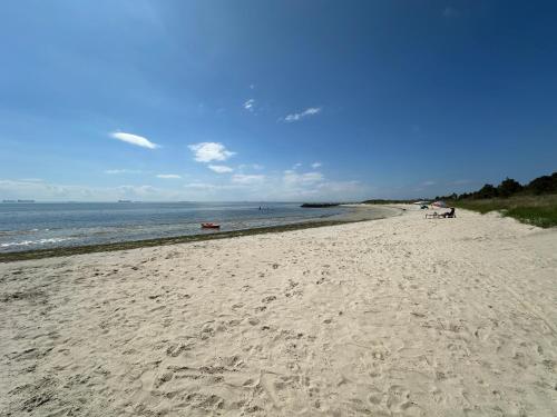 a sandy beach with people on it and the ocean at Isla Villa - Comfortable Bay Creek townhome with pools & golf! in Cape Charles