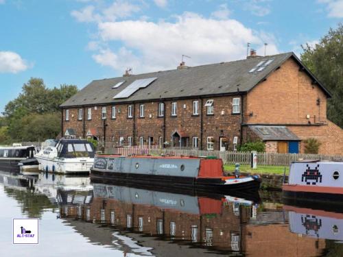 a boat is docked in front of a brick building at Calder Row by Alt-Stay Contractor Accommodation - 3 Bed Canal Side Contractor Home With Parking, Wi-Fi & Full Kitchen - Ideal For Long stays in Wakefield