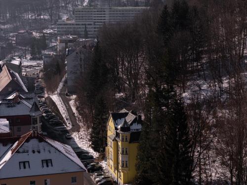a yellow building in a city with snow on the ground at Hotel Vera in Jáchymov