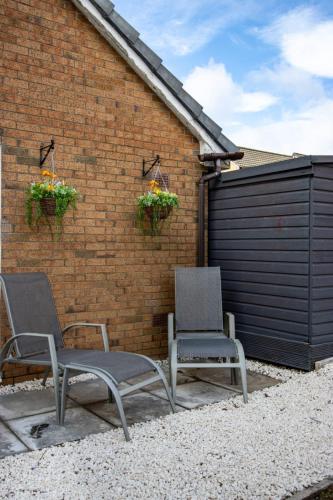 two chairs sitting on a patio next to a brick wall at Harvest House with Games Room in Stirling