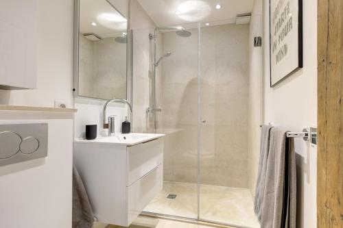 une salle de bain blanche avec une douche et un lavabo dans l'établissement l'authentique coeur de Paris, à Paris