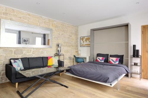 une chambre avec un lit et un mur en pierre dans l'établissement l'authentique coeur de Paris, à Paris