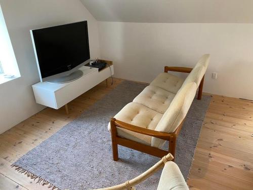 a living room with a chair and a flat screen tv at Beautiful Home In Ørsted W- in Ørsted
