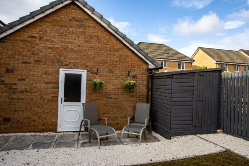 a brick building with two chairs and a fence at Harvest House with Games Room in Stirling