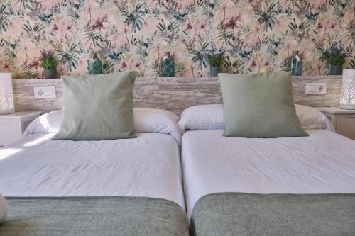 two beds in a room with floral wallpaper at Pensión A Solaina in O Pedrouzo