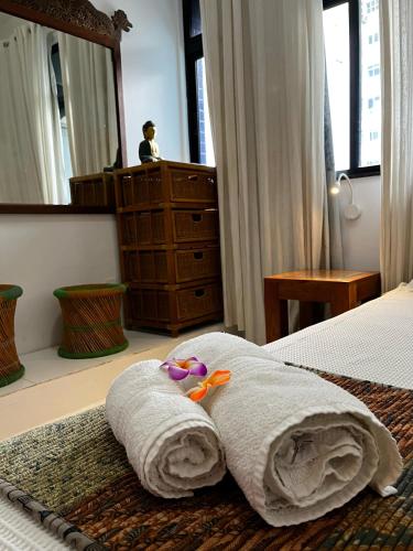 a bedroom with a bed with a towel and a dresser at Casa Petunia Pousada Boutique in Salvador