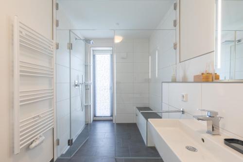 a white bathroom with a sink and a mirror at Auszeit am Deich in Nordstrand