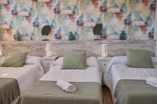 a room with three beds with pillows and a mural at Pensión A Solaina in O Pedrouzo