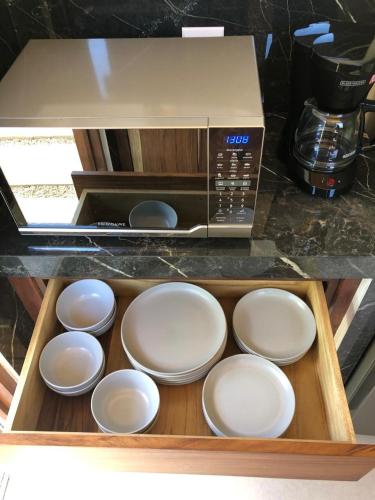a box of white plates in front of a microwave at Casa Manzu in Nosara