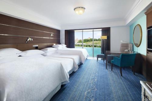 a hotel room with three beds and a desk at Sheraton Grande Tokyo Bay Hotel in Urayasu