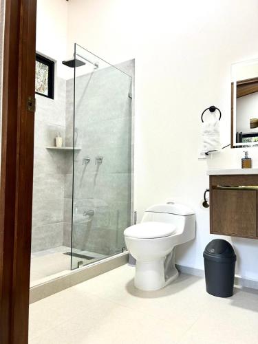 a bathroom with a toilet and a glass shower at Casa Manzu in Nosara