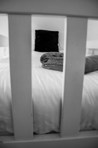a bed with white sheets and a black pillow at Harvest House with Games Room in Stirling