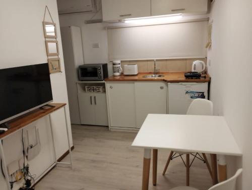 a small kitchen with a white table and a television at Cabaña Lo de Mingo in San Antonio de Areco
