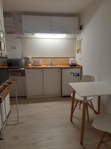 a kitchen with white cabinets and a sink and a table at Cabaña Lo de Mingo in San Antonio de Areco
