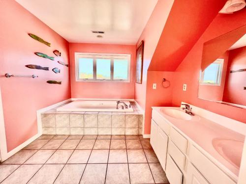 an orange bathroom with a tub and a sink at La Vie - Waterfront, boat dock & Pool! in Chincoteague