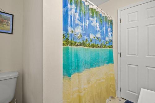 a bathroom with a shower curtain with a beach at Lazy Days - Pet friendly with screened gazebo! in Deep Hole