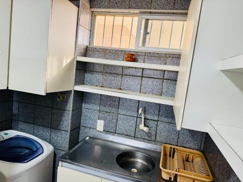 een kleine keuken met een spoelbak en een wasmachine bij Vista mar, piscina, na praia do futuro, com Ar condicionado e Wi-Fi in Fortaleza
