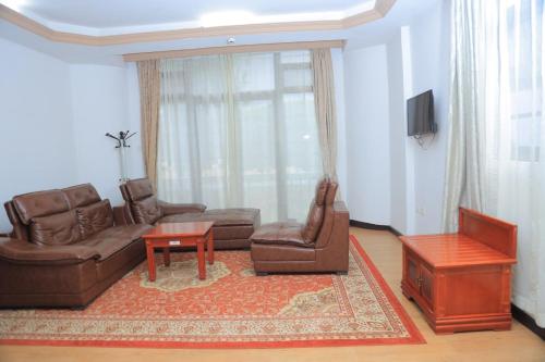 a living room with a couch and chairs and a tv at Central Jimma Hotel in Jīma