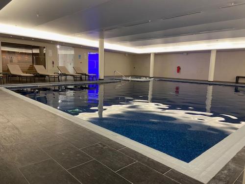a swimming pool with blue water in a building at Luxury 1 bed flat, minutes from Canary Wharf and South Quay Station in London