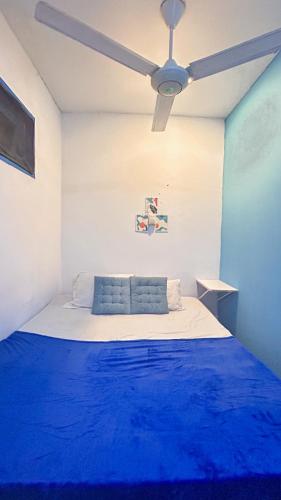 a bedroom with a blue bed with a ceiling fan at Santorini House in Bali Near Airport in Kuta