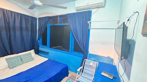 a room with a bed and a tv and a window at Santorini House in Bali Near Airport in Kuta