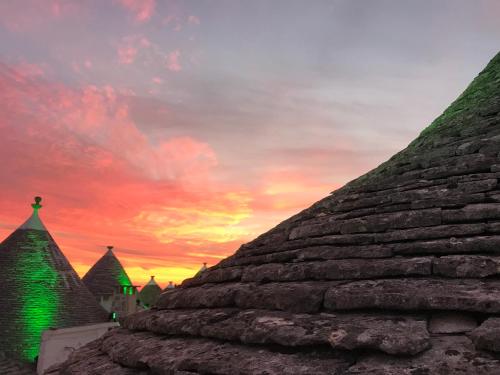 a sunset over the roofs of a building with green lights at Tipico Suite in Alberobello
