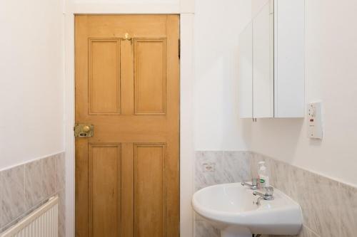 a bathroom with a sink and a wooden door at Aberdeen City Flat, close to city centre in Aberdeen