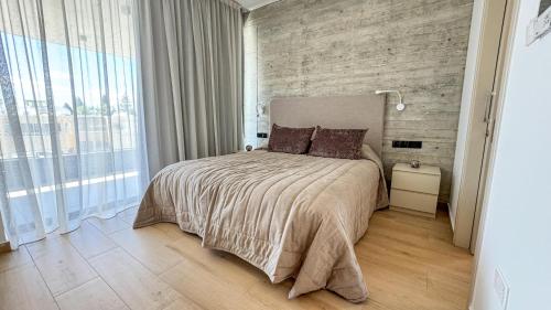 a bedroom with a large bed and a brick wall at Malberry Park 202 - Modern 2bedroom Apt with Shared Heated Pool, Sauna, Gym, Jacuzzi in Paphos City
