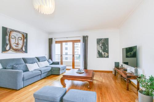 a living room with a blue couch and a table at Seu refúgio perfeito in Famões