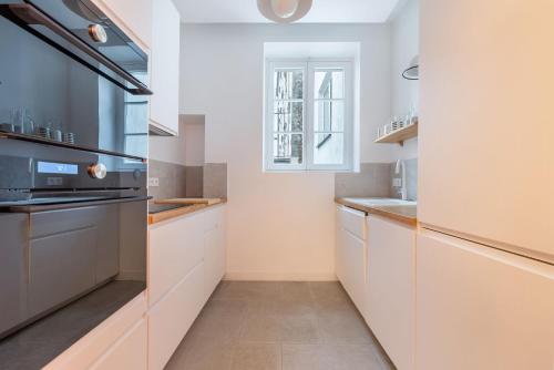 une cuisine avec des armoires blanches et une fenêtre dans l'établissement Mousquetaire, à Paris