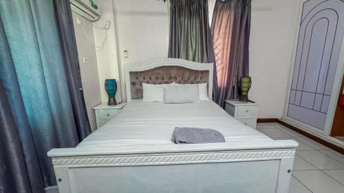 a bedroom with a large white bed with blue curtains at The Rosebay Apartment in Mombasa